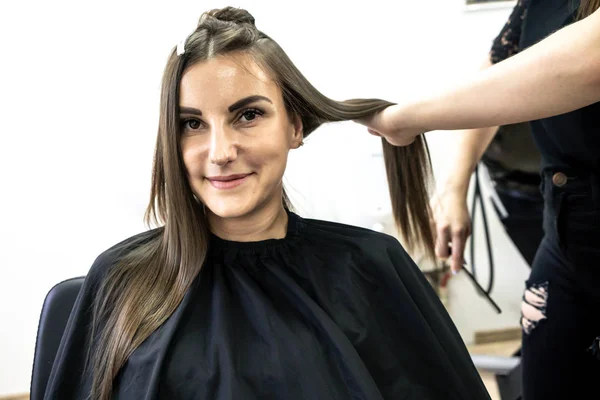 Jolie fille avec de longs cheveux bruns coiffeur faire de la stratification des cheveux dans un salon de beauté. concept de soins capillaires traitement — Photo