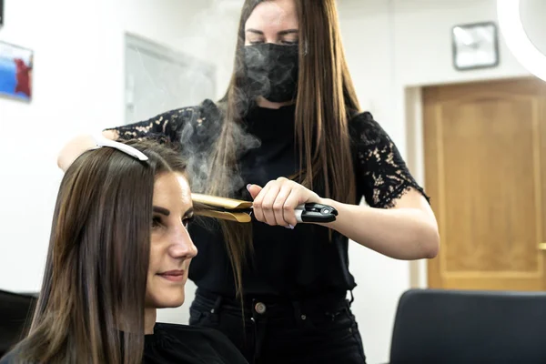 Coiffeur fait stratification des cheveux dans un salon de beauté pour une fille aux cheveux bruns. concept de soins capillaires . — Photo