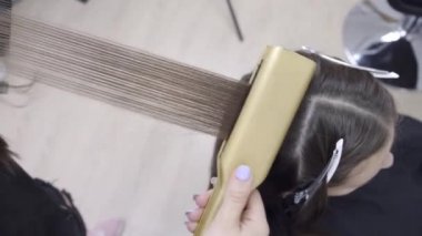 Kuaför kahverengi saçlı bir kız için bir güzellik salonunda laminasyon ve saç düzleştirme yok. saç bakım konsepti