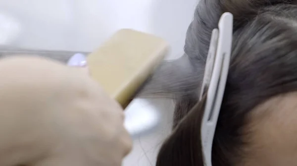 Coiffeur fait la stratification et le lissage des cheveux dans un salon de beauté pour une fille aux cheveux bruns. concept de soins capillaires — Photo