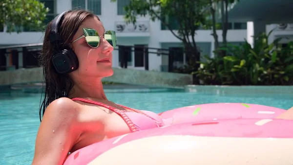 Femme heureuse et anneau de natation gonflable en forme de beignet dans la piscine et écoute de la musique au magasin . — Photo