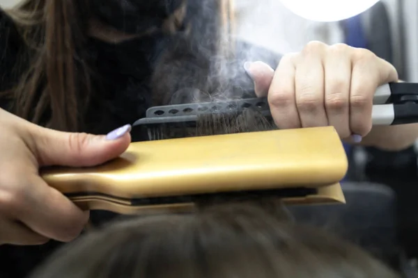 Cute girl with long brunette hair hairdresser doing hair lamination in a beauty salon. concept of hair care treatment, steam from hair — Stock Photo, Image