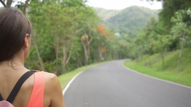 美丽的雨林与一个年轻的女旅行者在通往森林的泰国。女性走在雨林道路上，欣赏自然美景 — 图库视频影像