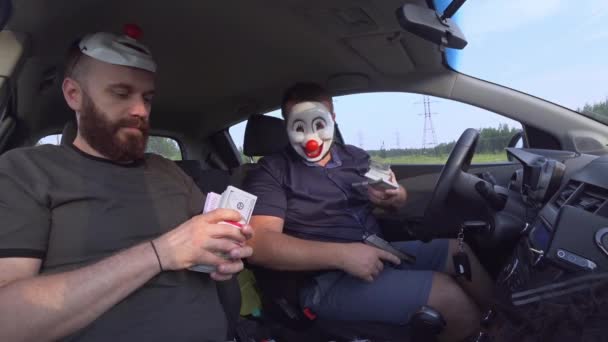 Twee mannen in grappige maskers met wapens in de auto verdelen het geld na de overval. Gewapende Rovers gebruikten wapens om geld te beroven. — Stockvideo