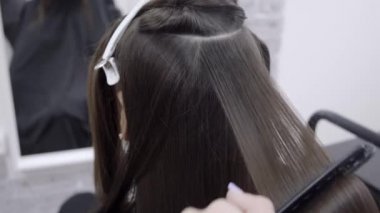 Uzun esmer saç Kuaför ile sevimli kız bir güzellik salonunda saç laminasyon yapıyor. saç bakım tedavisi kavramı 