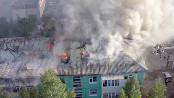 Hořící střecha obytně vysoké budovy, oblaka kouře z ohně. Hasiči uhasit oheň. pohled shora — Stock video