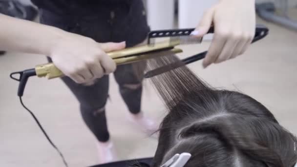 Cabeleireiro faz laminação de cabelo em um salão de beleza para uma menina com cabelo morena. conceito de cuidado do cabelo . — Vídeo de Stock