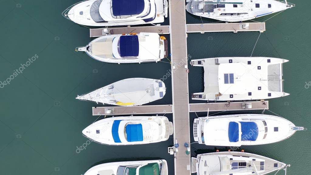 Aerial View by Drone of Yacht Club and Marina. Top view of yacht club. White boats in sea water. Marina dock yachts and small moto. Yacht and sailboat