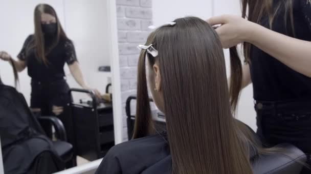 Cute girl with long brunette hair hairdresser doing hair lamination in a beauty salon. concept of hair care treatment — Stock Video