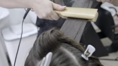 Kuaför kahverengi saçlı bir kız için bir güzellik salonunda laminasyon ve saç düzleştirme yok. saç bakım konsepti