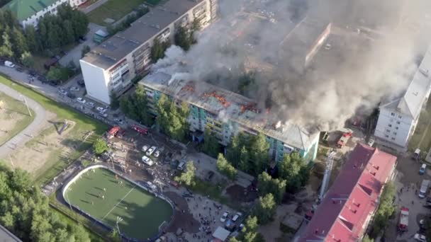 Nizhnevartovsk, Rusia - 1 de julio de 2019: los bomberos apagan un incendio en el techo de un edificio residencial de gran altura. vista superior — Vídeo de stock