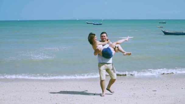 Man in Love neemt de vrouw op zijn armen en draait haar rond aan de kust. — Stockvideo