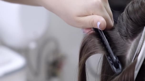 Cabeleireiro faz laminação e alisamento de cabelo em um salão de beleza para uma menina com cabelo marrom. conceito de cuidado do cabelo — Vídeo de Stock