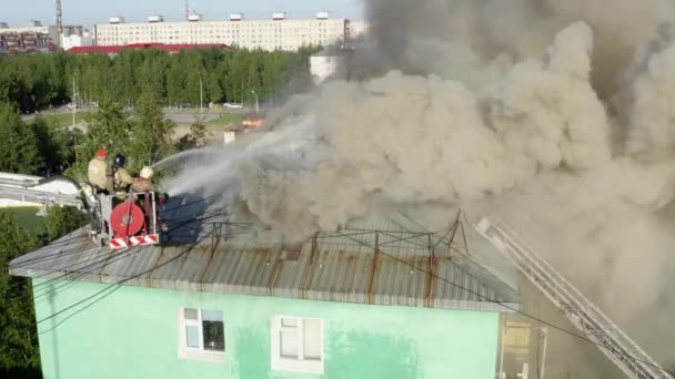 Nizhnevartovsk, Rusia - 1 de julio de 2019: los bomberos apagan un incendio en el techo de un edificio residencial de gran altura. vista superior — Vídeos de Stock