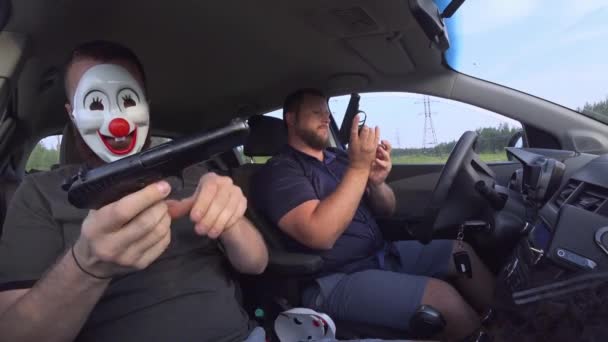 Två män i roliga masker med vapen i bilen förbereder sig för rån. Beväpnade rånare använde vapen för att råna pengar. — Stockvideo