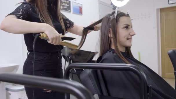 Nizhnevartovsk, Rússia - Julho 1, 2019: cabeleireiro faz laminação de cabelo em um salão de beleza para uma menina com cabelo morena. conceito de cuidado do cabelo . — Vídeo de Stock