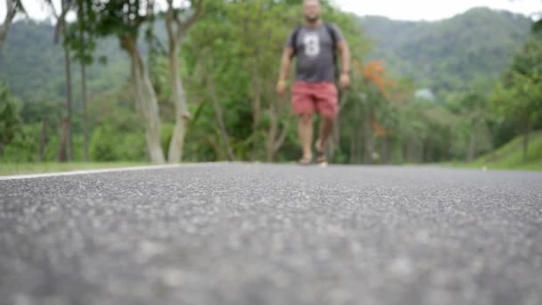파타야, 태국 - 5 월 22, 2019 : 태국 숲으로 가는 길에 배낭을 가진 여행자 젊은 남자와 잘 생긴 열대 숲. 한 남자가 열대 도로를 걷고 자연의 전망을 즐깁니다. — 비디오