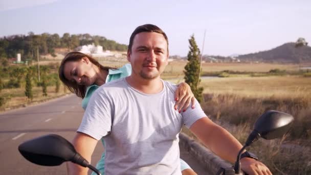 Deux hommes et deux femmes font de la moto le long de la route entre les plantations et les collines verdoyantes . — Video