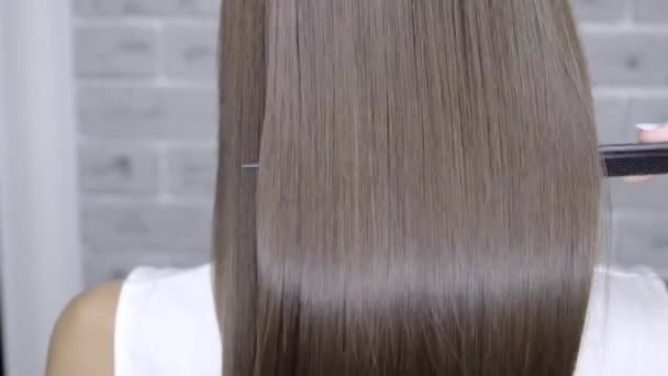 Результат после ламинирования и выпрямления волос в салоне красоты для девушки с каштановыми волосами. уход за волосами — стоковое видео