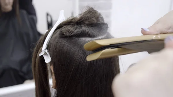 Coiffeur fait stratification des cheveux dans un salon de beauté pour une fille aux cheveux bruns. concept de soins capillaires . — Photo