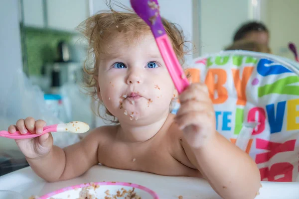 Feliz divertido poco asiático chica comiendo desayuno y ella celebración cuchara en su manos — Foto de Stock