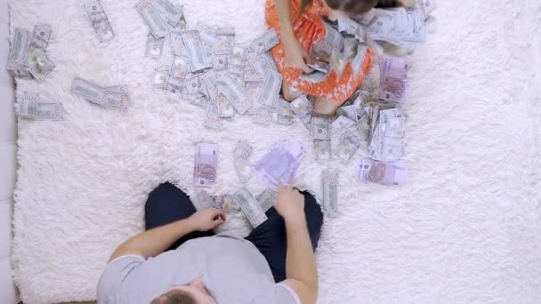 Жінка і чоловік кидають один одному багато банкнот доларів на ліжко, повільний рух, вид зверху — стокове відео