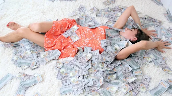 Many banknotes fly in the air overhead in slow motion. A girl lies and a lot of money falls on her. happy woman rejoices. Huge wealth of money, slow motion, top view — Stock Photo, Image