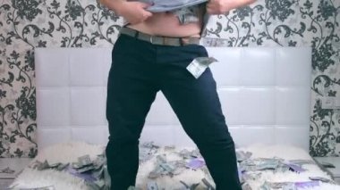erkek muazzam bir zenginliğe sahiptir. bir adam beyaz bir yatakta banknotlar bir sürü dağılar, para atar, bel-yüksek, bir yüz olmadan.