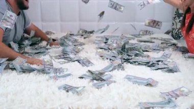 Kadın ve erkek yatakta dolar banknotlar bir sürü tırmık, yavaş hareket, üst görünümü