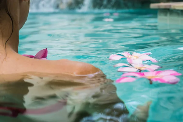 Kobieta w basenie. Tropikalne kwiaty Frangipani Plumeria, Leelawadee pływających w wodzie. Basen spa. Spokój i cisza. Koncepcja Spa. — Zdjęcie stockowe