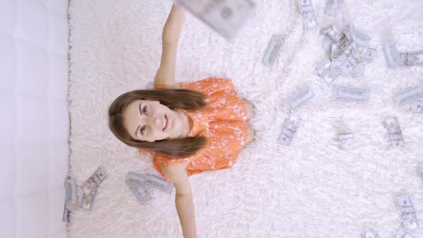 Велика кількість грошей падає на біле ліжко жінки. Дівчинка отримує багато грошей. повільний рух. Величезне багатство грошей, вид зверху — стокове відео