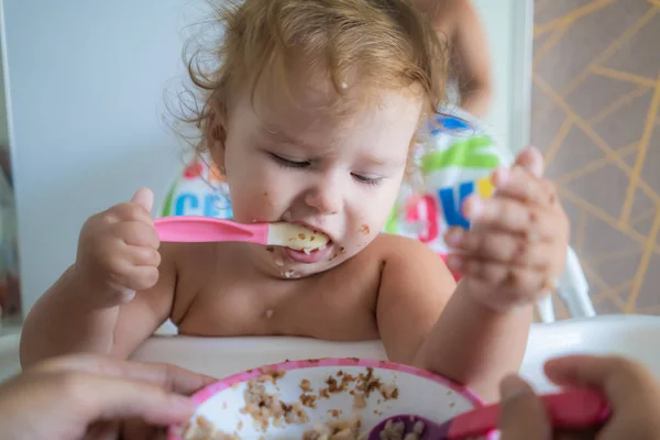 Feliz divertido poco asiático chica comiendo desayuno y ella celebración cuchara en su manos — Foto de Stock