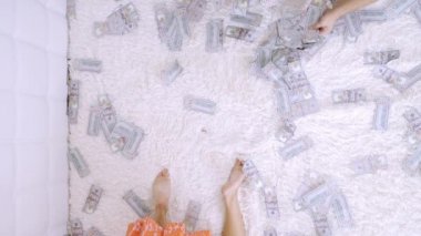 Kadın ve erkek yatakta dolar banknotları bir sürü saymak, yavaş hareket, üst görünümü