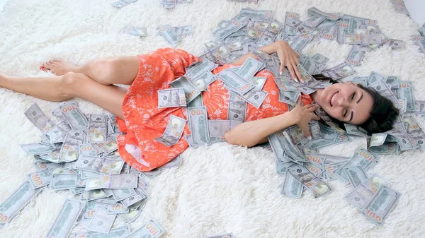 Many banknotes fly in the air overhead in slow motion. A girl lies and a lot of money falls on her. happy woman rejoices. Huge wealth of money, slow motion, top view — Stock Photo, Image