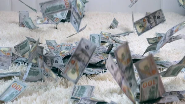 Birçok banknot yavaş çekimde beyaz bir yatakta havada uçar. Büyük para zenginliği, yavaş çekim, üst görünüm — Stok fotoğraf