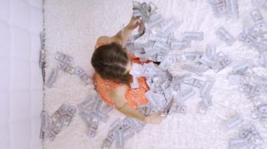 Güzel bir kız muazzam zenginlik sahiptir. kadın beyaz bir yatakta banknot bir sürü sıralama, para, yavaş hareket, üst görünümü atar