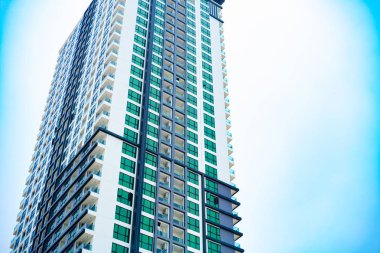 Kurumsal yüksek katlı bina mavi gökyüzü ve bulutlar görülen.