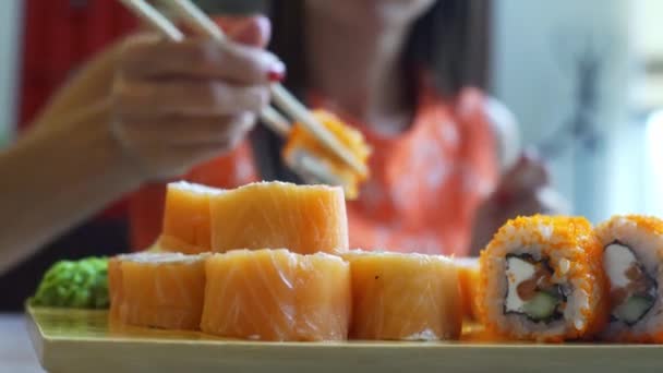 La hembra en la cafetería come sushi con palillos. Primer plano de sushi . — Vídeos de Stock