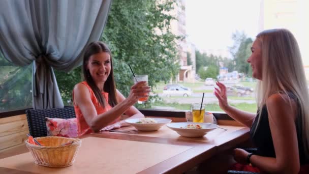 Dos amigos en un bar-cafetería beben cócteles en una terraza abierta . — Vídeos de Stock