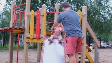 Baba ve kızı oyun alanında oynamak, bir adam bir çocuk slayt aşağı hareket eden bir kızı yakalar.