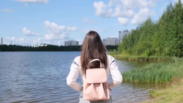 Μελαχρινή κορίτσι με ένα σακίδιο απολαμβάνει εκπληκτική γραφική θέα. Λίμνη και όμορφο τοπίο. Περιπέτεια, ελευθερία, τρόπος ζωής — Αρχείο Βίντεο