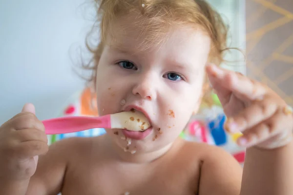 Ευτυχισμένο αστείο μικρή ασιάτισσα τρώει πρωινό και κρατά κουτάλι στα χέρια της — Φωτογραφία Αρχείου