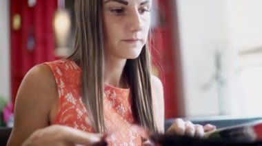 Elinde bir menü ile bir kafede Sevimli kadın, bir kadın sipariş yapmak için menüde yiyecek ve içecekler seçer.