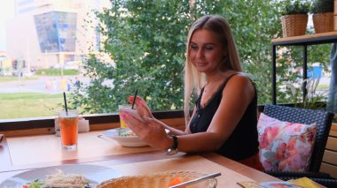 güzel sarışın kadın telefonda sohbet, skype konuşurken ve bir kokteyl içme, sokakta bir kafede oturan.