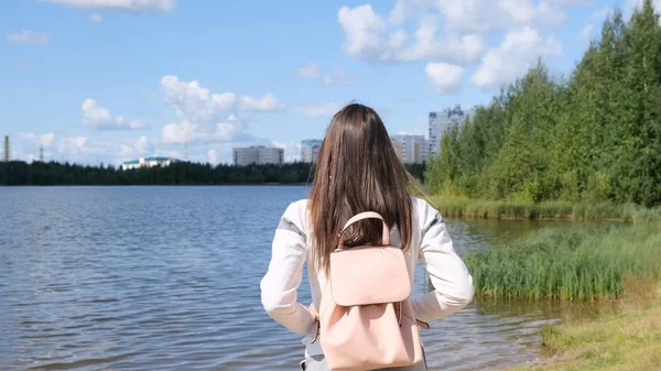 Chica morena con una mochila disfruta de impresionantes vistas panorámicas. Lago y hermoso paisaje. Aventura, libertad, estilo de vida — Foto de Stock