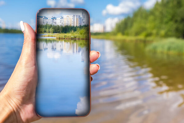 Taking photo on mobile phone concept. Hand holding mobile smart. Phone with lake view.