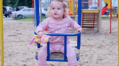 Nizhnevartovsk, Rusya - 15 Ağustos 2019: Küçük kız 2 yaşında bir yaz sonbahar gününde oyun alanında salıncak taslanıyor.