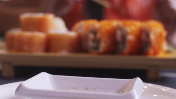 Női kéz pour szójaszósz egy mini-vízforraló egy serpenyőben, mellette sushi — Stock videók