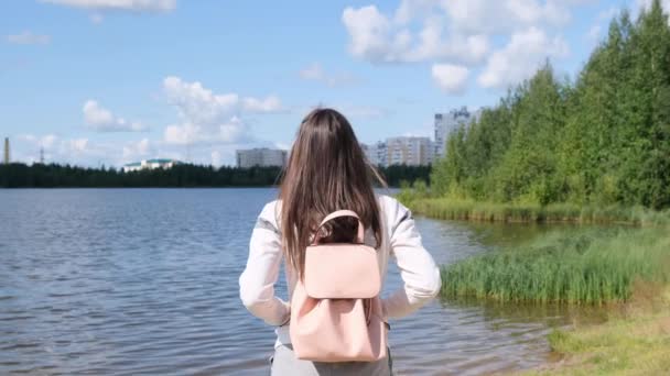 Brunetka s batohu má nádherný výhled. Jezero a krásná krajina. Dobrodružství, svoboda, životní styl — Stock video