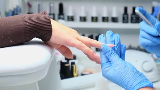 Close-up shot van een vrouw in een nagel salon een manicure door een schoonheidsspecialiste met nagelvijl ontvangen. Vrouw krijgen nagel manicure. Schoonheidsspecialiste bestand nagels aan een klant. — Stockvideo